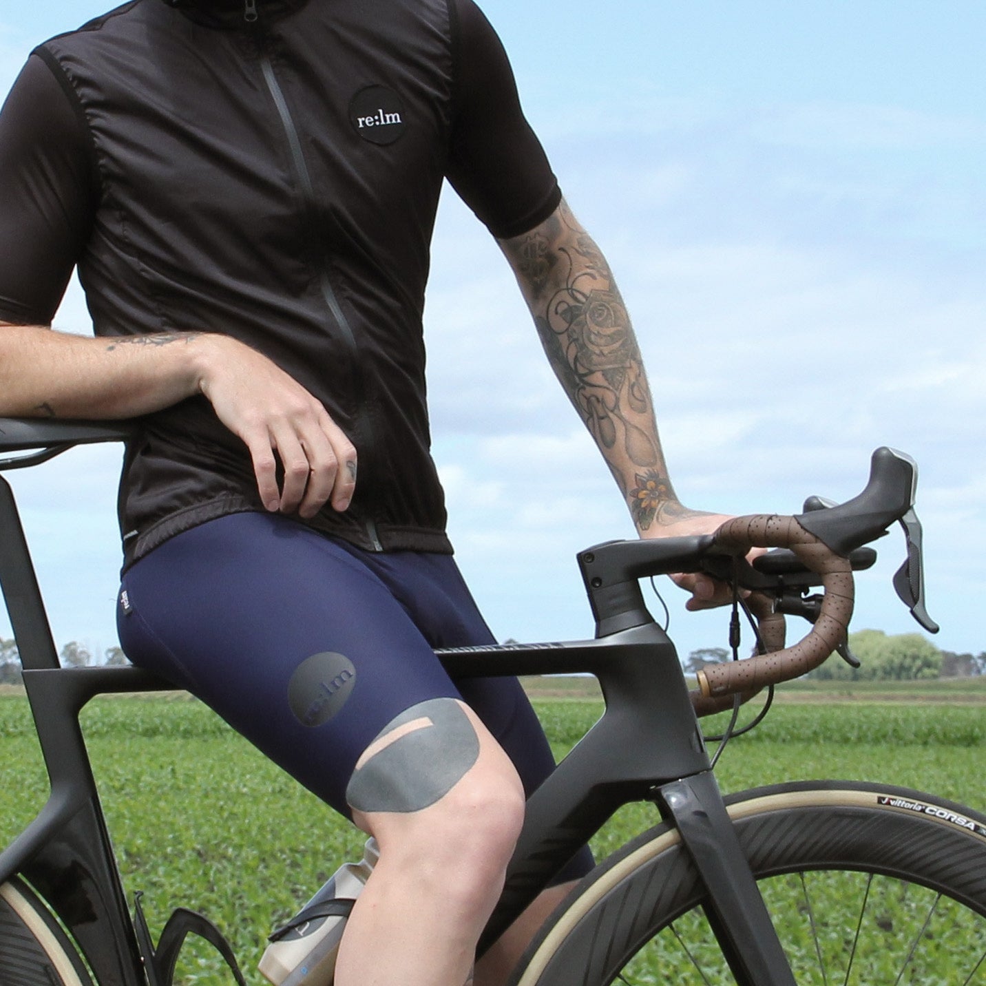 Man on bike wearing Relm Cycling black gilet and navy bib shorts